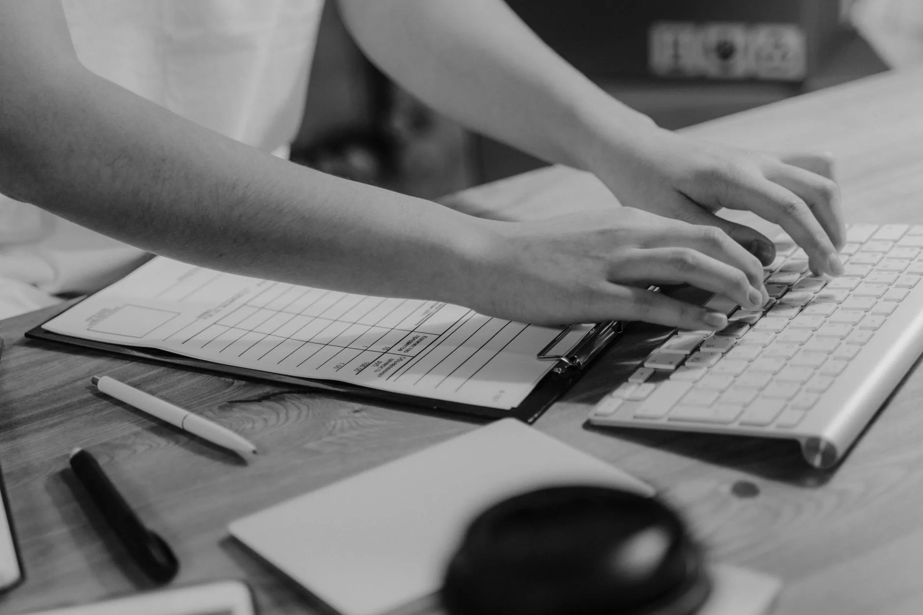 Mains tapant sur un clavier avec un clipboard et des formulaires sur un bureau
