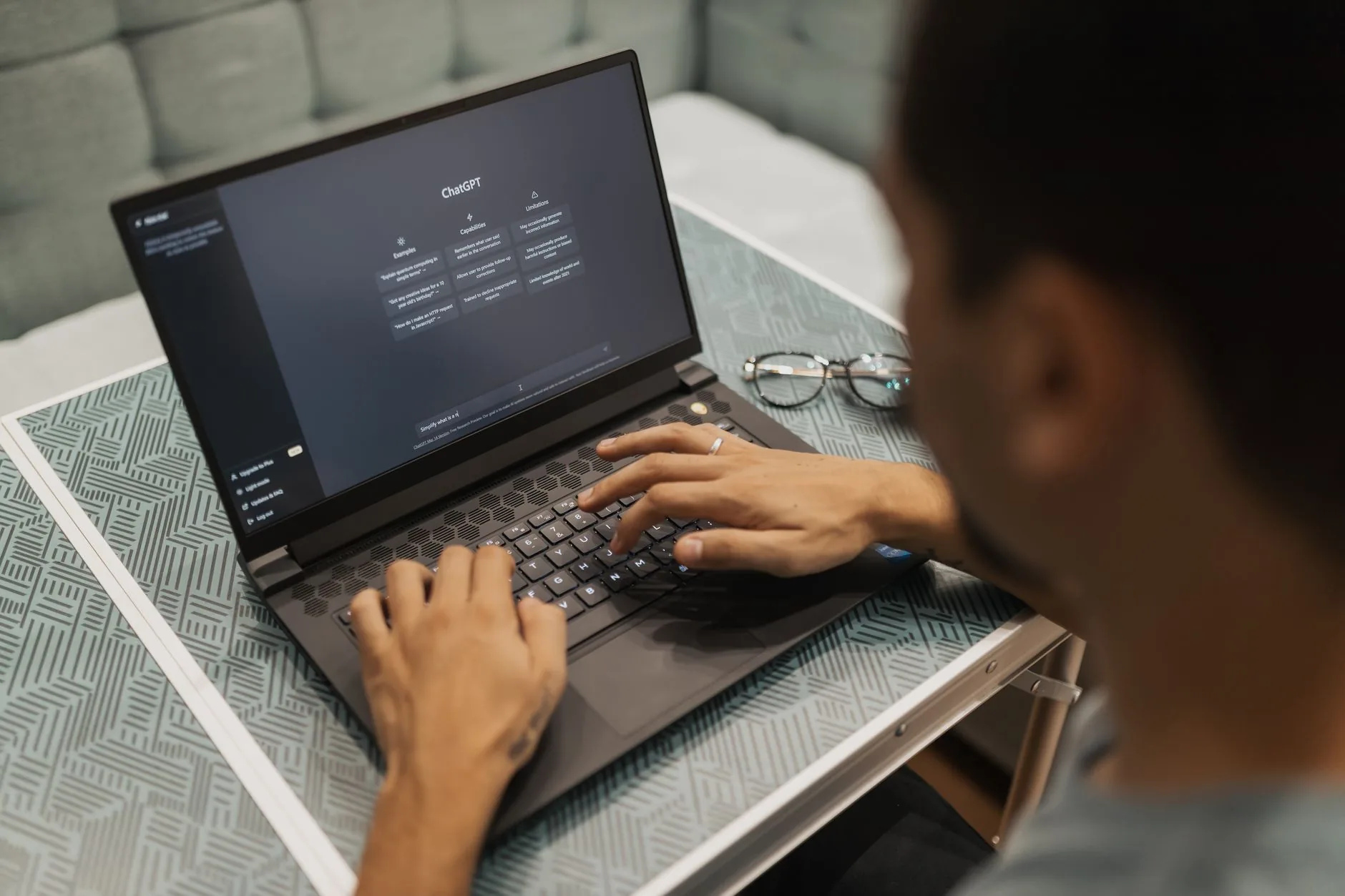 Une personne utilise un ordinateur portable affichant l'interface de ChatGPT dans un cadre intérieur